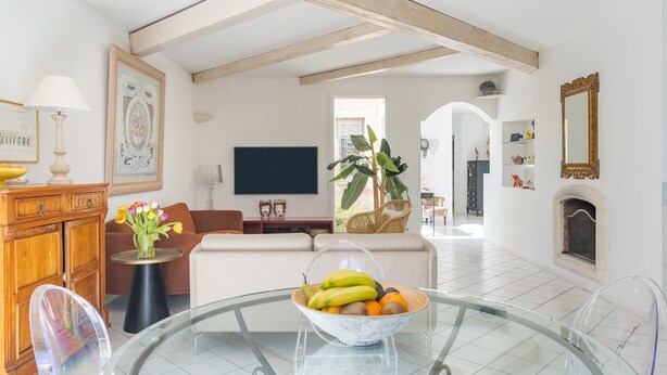 Un salón con sofá, televisor y un frutero sobre una mesa de vidrio.