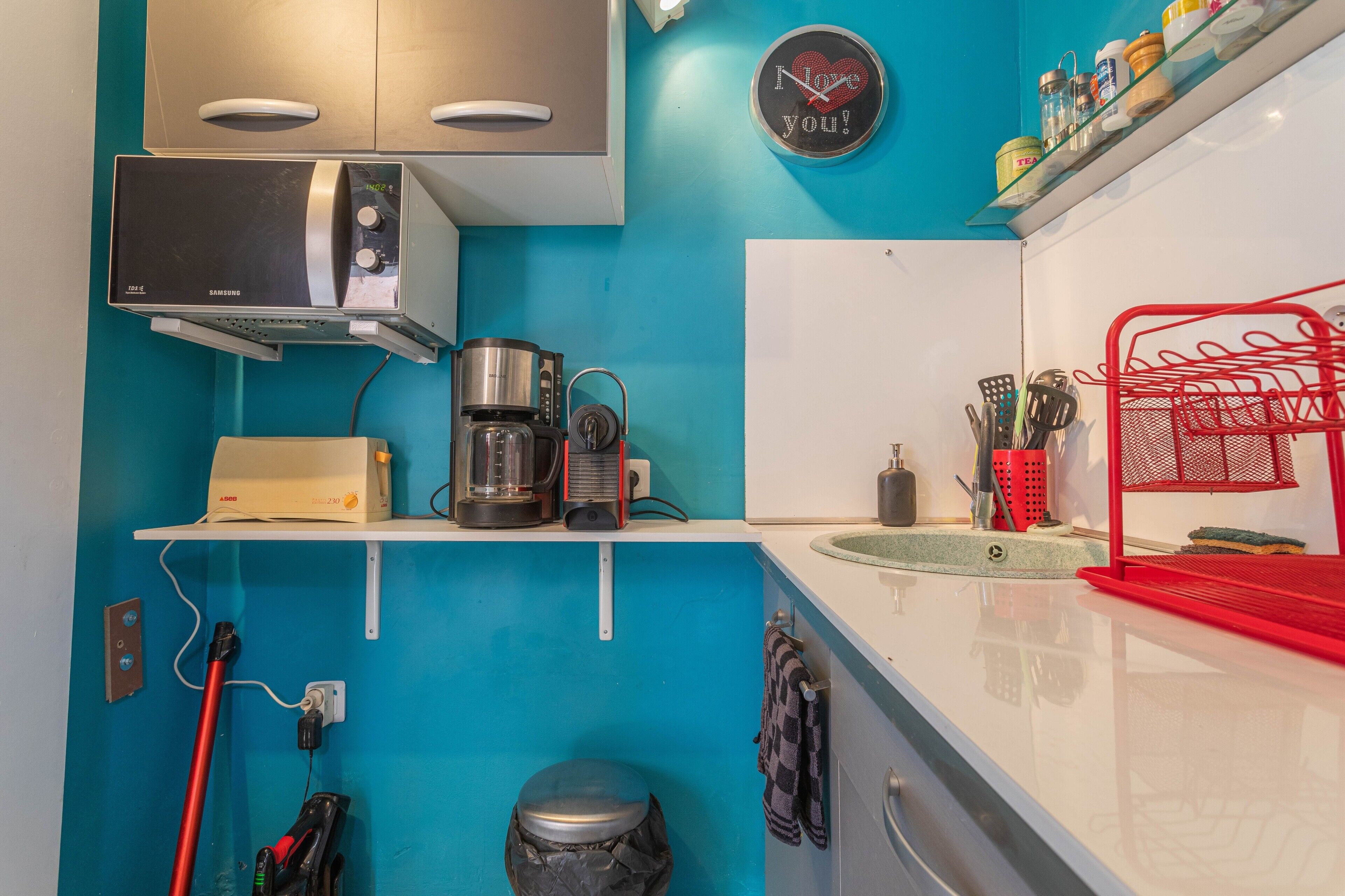 A kitchen with a microwave, coffee maker, and a red basket.