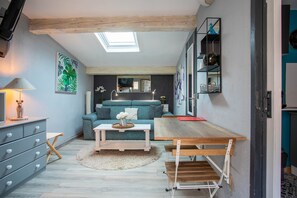Un espacio habitable compacto con sofá, mesa de comedor, lámpara y espejo.