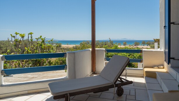 A balcony with a lounge chair, a view of the beach, and a clear sky. - Holiday Apartment "Maria's Village Suite" with Sea View, Private Terrace & Wi-Fi (Paros)