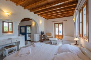 A bedroom with a wooden ceiling, a desk, a chair, a television, and a bed. - Studio Apartment "Maria's Village One Bedroom House 4" with Sea View, Private Terrace & Wi-Fi (Paros)