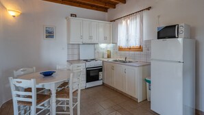 Une cuisine de taille réduite avec des meubles blancs, une cuisinière, un four à micro-ondes et un évier.