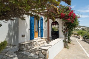 A white building with blue shutters, stone steps, and a view of the countryside.