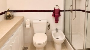 Un baño con inodoro, bidé y ducha.