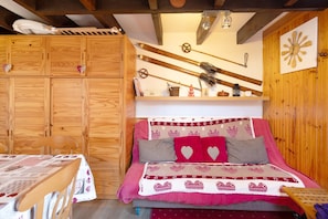 Ein Holzblockhaus-Interieur mit einem Bett, einem Tisch und Skiern an der Wand.