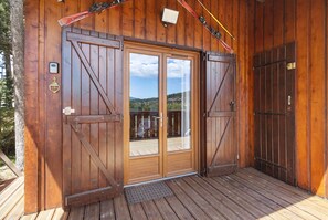 A wooden cabin with a large sliding door, a small porch, and a view of the surrounding landscape. - Chalet 'Petit Chalet' semi-detached at Pyrénées 2000 with mountain view, private terrace and Wi-Fi (Bolquère)