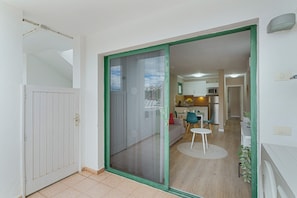 A room with a sliding glass door leading to a kitchen and living area, a small round table, and a sofa.