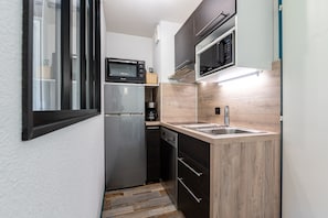 A compact kitchen with a refrigerator, microwave, oven, and sink. - Apartment 'Appartement 4-6 Personnes' with Mountain View, Balcony and Wi-Fi (Saint-François-Longchamp)