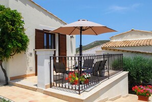 A patio with a table, chairs, and an umbrella. There are potted plants and a railing around the patio. - Appartamento Alba - Le 3 Rose Apartments (Sicilia)