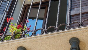 A balcony with wrought iron railings, a tiled roof, and a stucco wall. - Appartamento Alba - Le 3 Rose Apartments (Sicilia)