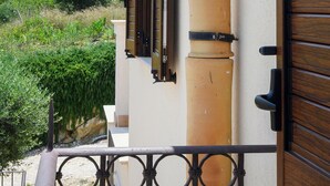 A building with a beige facade, a large beige column, and a wooden door with a black handle. - Appartamento Alba - Le 3 Rose Apartments (Sicilia)