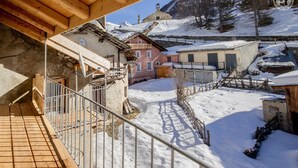 A snowy village with traditional buildings, a wooden staircase, and a metal railing. - LA Maison Bleue - Bessans (BESSANS)