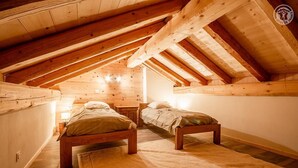A cozy attic bedroom with wooden beams, two single beds, and a bench. - LA Maison Bleue - Bessans (BESSANS)