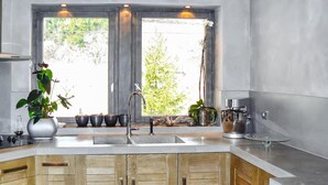 A modern kitchen with wooden cabinets, a stainless steel sink, and a large window with a view of greenery.
