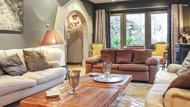 A living room with a sofa, armchairs, a coffee table, and a lamp.