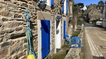 A stone building with blue shutters, a yellow buoy, and a narrow street.