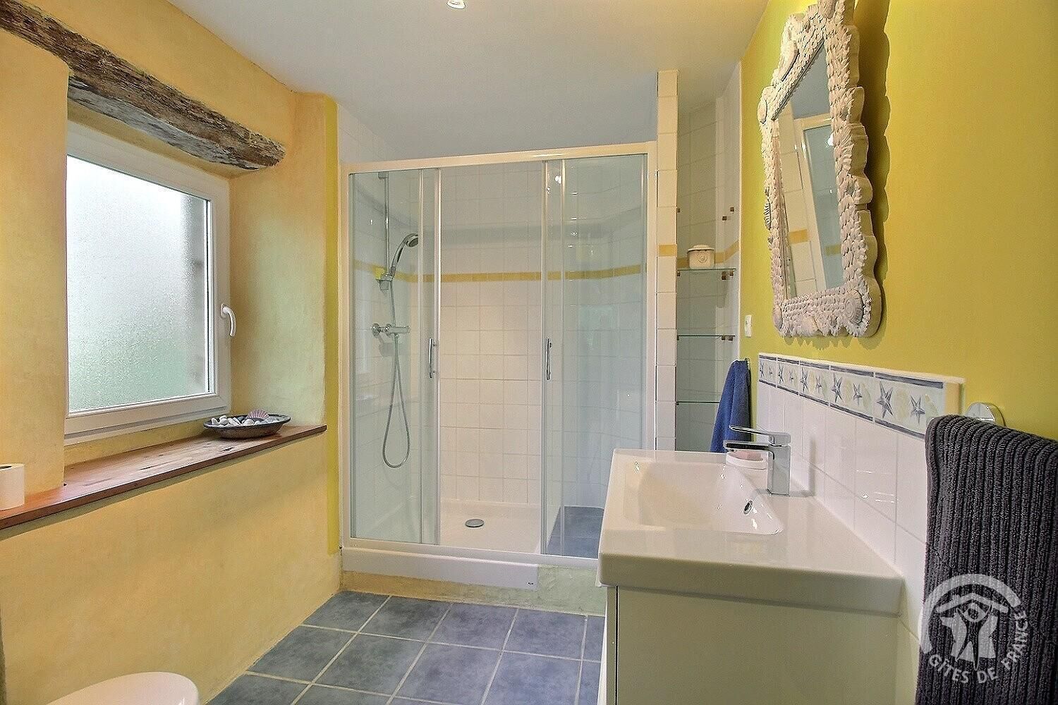 Une salle de bain avec une douche, un lavabo et une fenêtre.