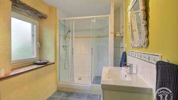 Une salle de bain avec une douche, un lavabo et une fenêtre.
