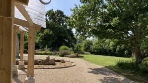 A gravel driveway leading to a wooden structure with a pergola.