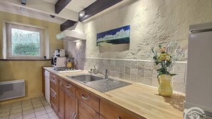 A kitchen with wooden cabinets, a double sink, a stove, and a window.
