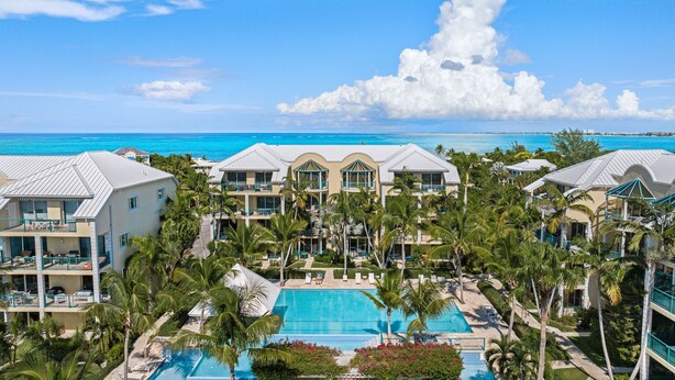 Ein Resort mit einem zentralen Pool, mehreren Balkonen und Blick auf den Ozean.