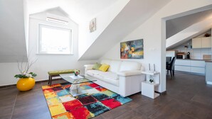 Eine moderne Wohnung mit einem weißen Sofa, einem farbenfrohen Teppich und einer Küche im Hintergrund.