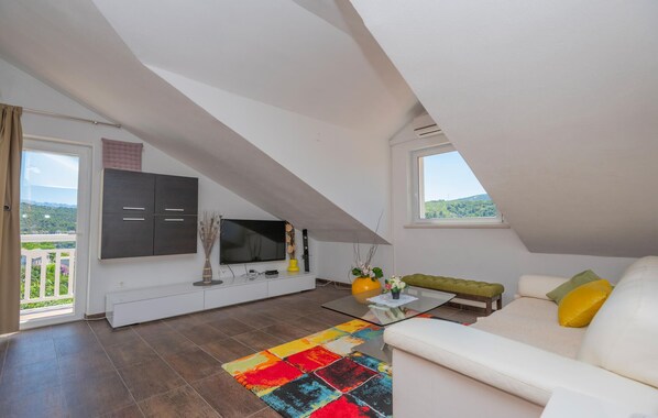 A modern loft apartment with a sloped ceiling, a large window offering a view of greenery, a white sofa with yellow pillows, and a colorful rug. - Amazing apartment in Pucisca (Pucisca)