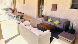 Een terras met een bank, stoelen en een tafel.