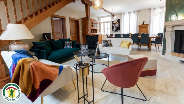 Een ruime woonkamer met een trap, een open haard en een eethoek.