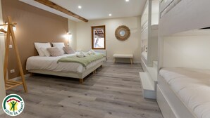 Een slaapkamer met een bed, een bankje, een ladder en een stapelbed.