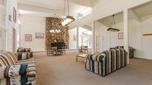 A spacious living room with a stone fireplace, two sofas, a dining table with chairs, and a chandelier. - Cozy/Relaxing Retreat in the 💖 of Mammoth, near 🏔⛷❄️🏌️🏊‍♀️🌊 (Mammoth Lakes)