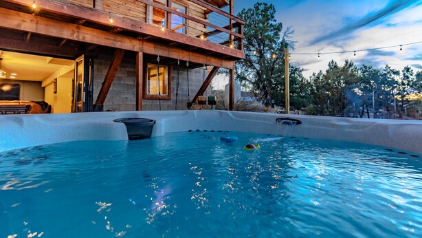 Une cabane en bois dotée d’un bain à remous et d’un balcon donnant sur une zone boisée.
