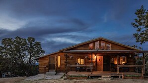 Une cabane en bois dotée d’une véranda, de grandes fenêtres et d’une porte d’entrée.