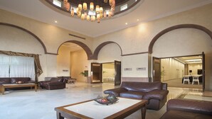 A spacious lobby with leather sofas, a coffee table, and a chandelier.