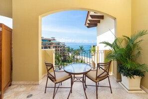 A balcony with a round table and chairs, overlooking a beach and a building complex. - Villa La Estancia NV by Villa TS Rentals (Nuevo Nayarit)