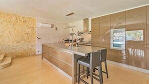 Una cocina moderna con una isla central, electrodomésticos de acero inoxidable y una pared decorativa de piedra.