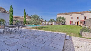 Un patio con piscina, mobiliario exterior y edificios de piedra.