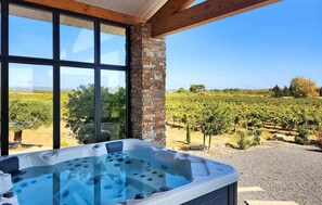 A hot tub with a vineyard view through large windows.