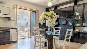 Une cuisine moderne avec une table à manger en verre, des chaises blanches et un arrangement floral décoratif blanc.