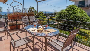 Une terrasse avec une table en verre, des chaises et des plantes en pot.