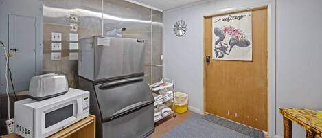 A kitchen with a refrigerator, microwave, and toaster on a wooden shelf.