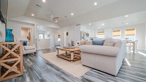 A spacious living room with a large beige sofa, a wooden coffee table, and a patterned rug. - Copano Bay, Rockport, Tx. Waterfront, Private Pool & Hot Tub, & Pier  (Rockport)