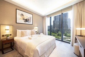 A hotel room with a large bed, two bedside tables, a city view, and a framed artwork on the wall.