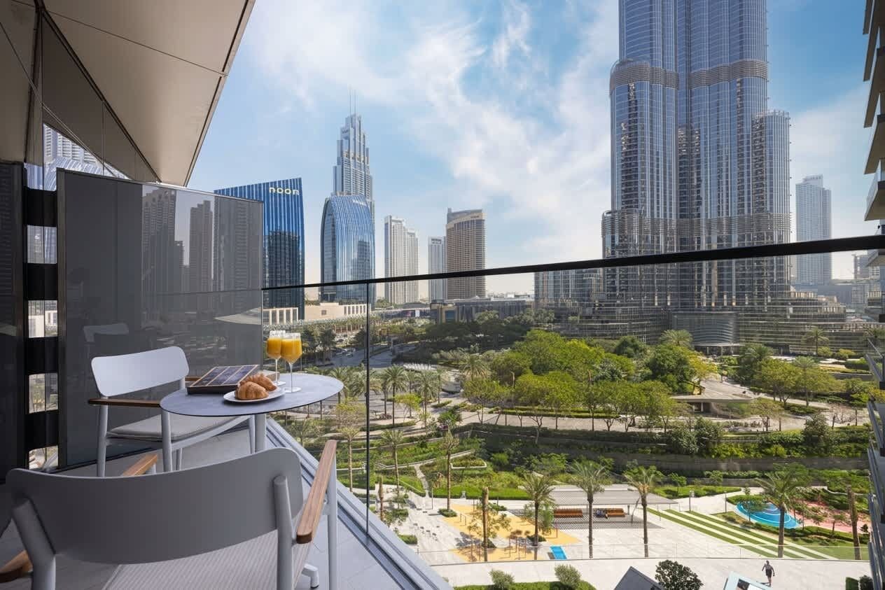A balcony with a table, chairs, and a view of a cityscape with modern buildings.