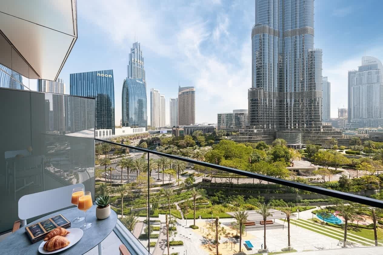 A balcony with a city view, a table with croissants and juice, and a potted plant.