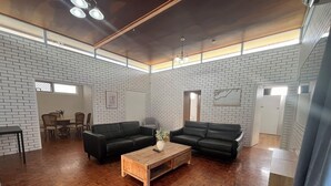 A spacious living room with a wooden coffee table, two black sofas, and a dining area with chairs. - Browns Broadbeach (Mermaid Beach)