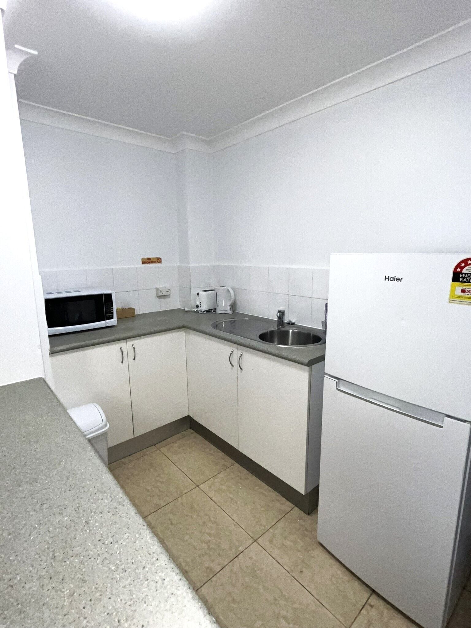 A small kitchen with white cabinets, a microwave, a toaster, and a refrigerator.