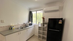 A compact kitchen with a microwave, sink, and black refrigerator. - Browns Broadbeach (Mermaid Beach)