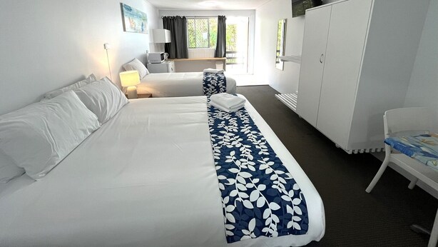 A hotel room with two beds, a wardrobe, a desk, a chair, a TV, and a ceiling fan. - Browns Broadbeach (Mermaid Beach)