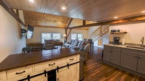 A spacious kitchen with wooden flooring, a central island, and a staircase leading to a loft area. - Historic Barn Suites (Greenville)